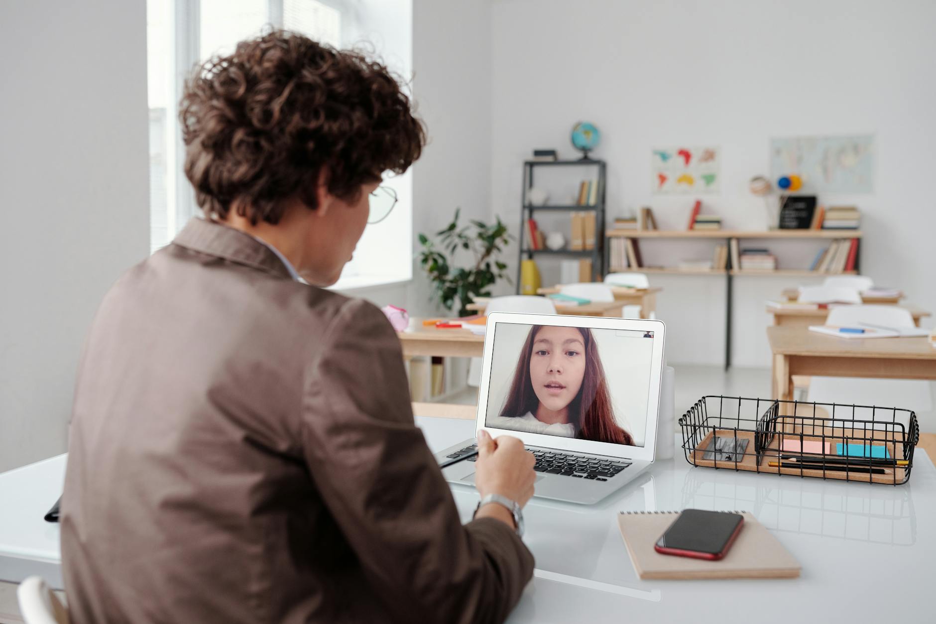 A teacher engages in an online class from an empty classroom, using a laptop for learning. (Photo by Max Fischer on Pexels)