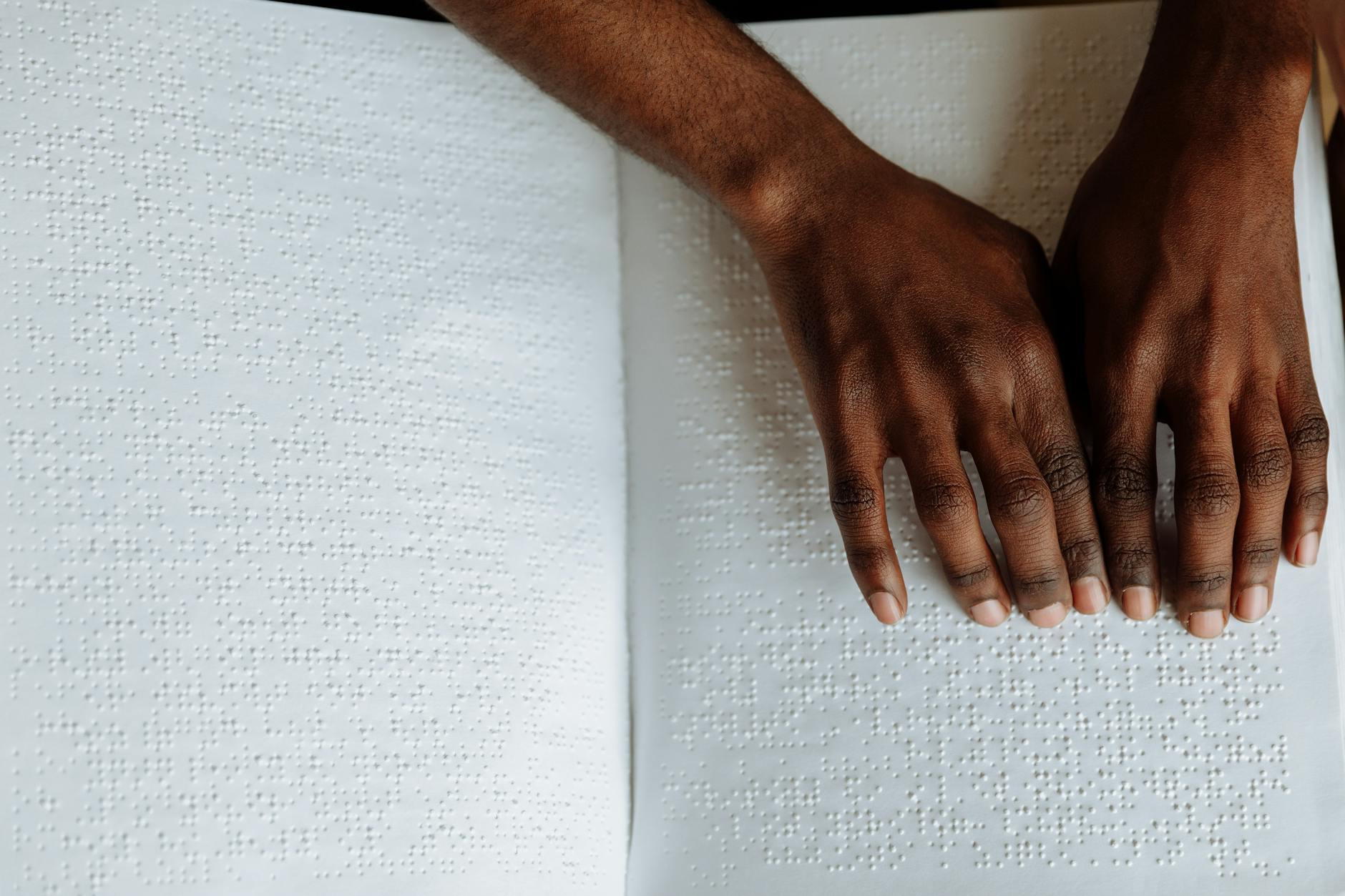 Close-up of hands reading a Braille book, highlighting tactile sensory perception for the visuall... (Photo by Thirdman on Pexels)