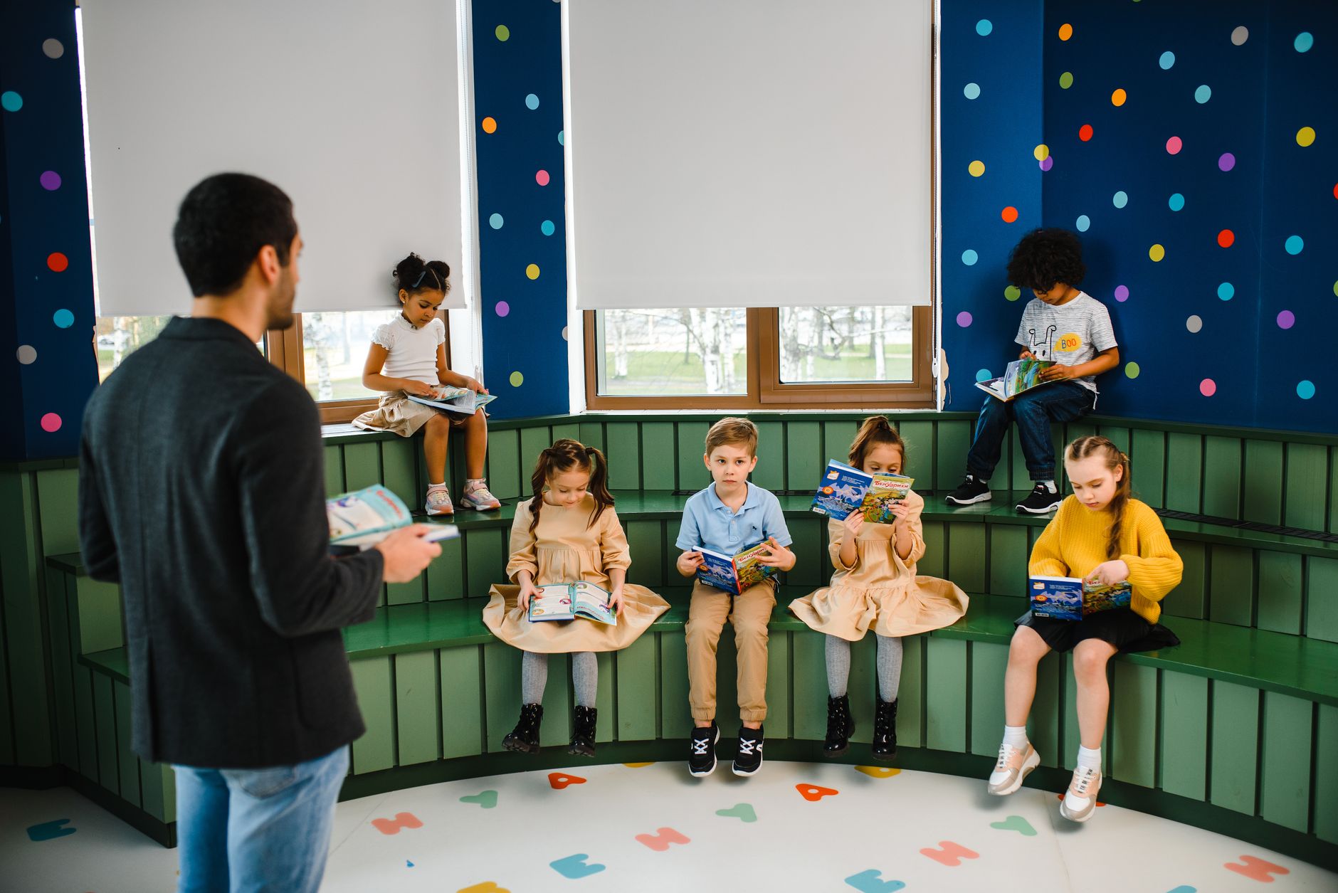 Preschool teacher leading storytime with children reading books in a colorful classroom setting. (Photo by Anastasia  Shuraeva on Pexels)